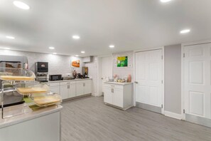 A modern kitchen with white cabinets, a coffee machine, and a microwave. - Quality Inn Gainesville near University (Gainesville)