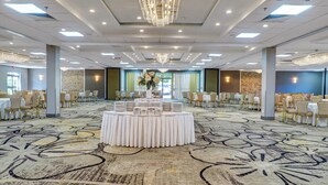A banquet hall with round tables, chairs, a chandelier, and a patterned carpet. - Holiday Inn Piscataway Somerset by IHG (Piscataway)