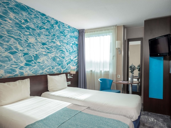 A hotel room with two beds, a large abstract mural, a TV, a small table with a chair, and a window with curtains. - ibis Styles Paris Val de Fontenay (Fontenay-sous-Bois)