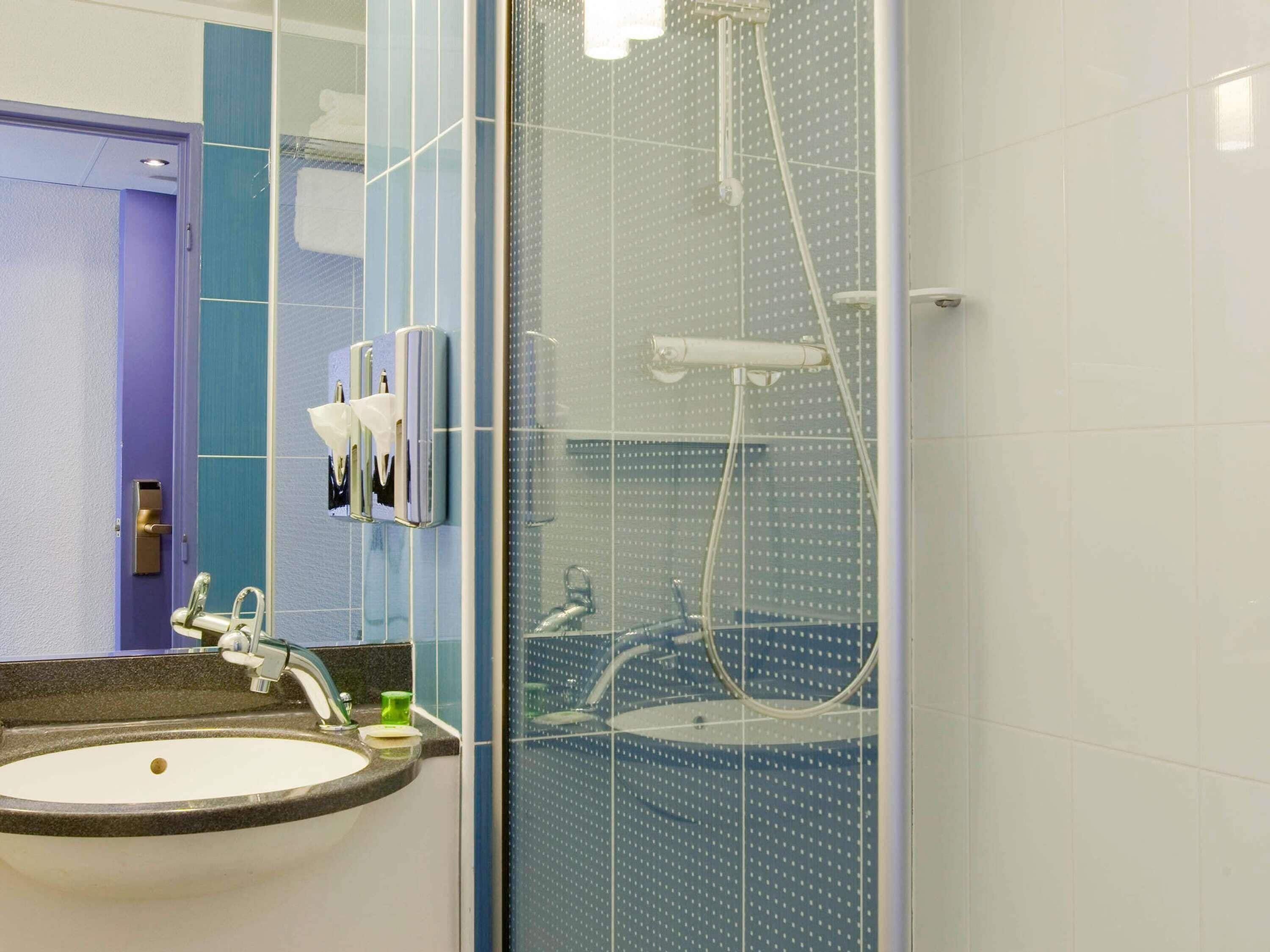 Une salle de bain avec un lavabo, un miroir et une douche.