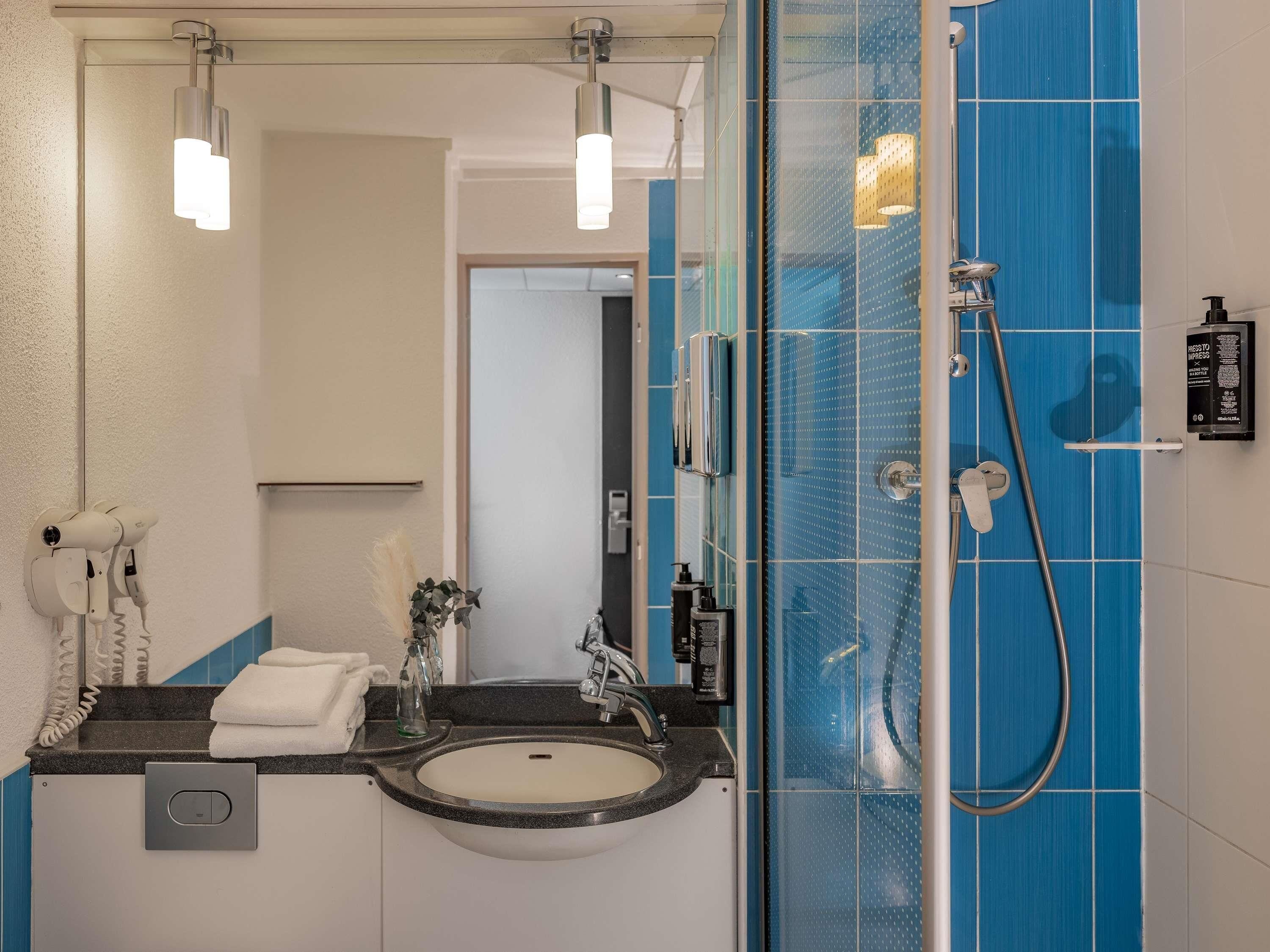 Un baño moderno con un espejo grande, un lavamanos y una ducha.
