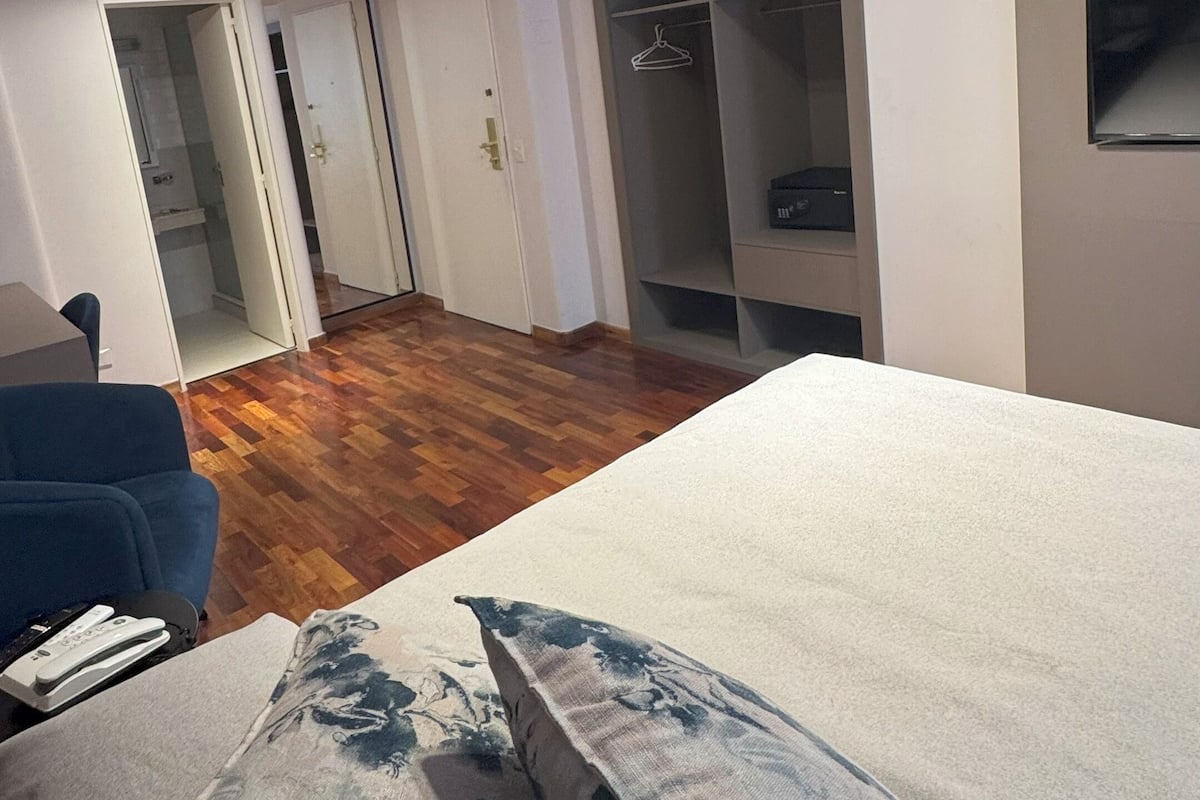 Une chambre à coucher comprenant un lit, une table de chevet, une armoire et un luminaire au plafond.