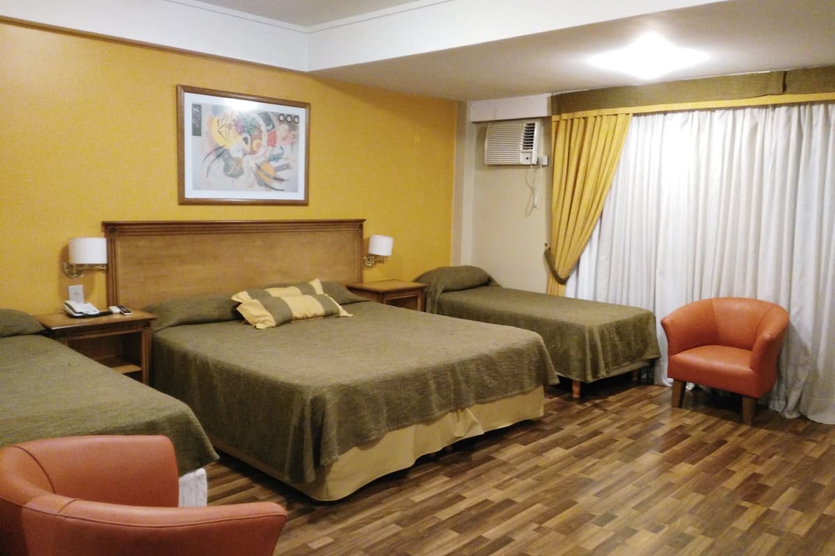 Une chambre d’hôtel avec deux lits, un plancher en bois, un tableau au mur et une chaise.
