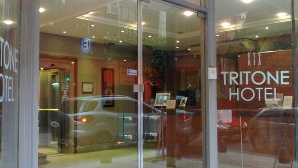 The Tritone Hotel entrance with glass doors, a visible elevator, and a car parked outside. - Tritone Hotel (Buenos Aires)