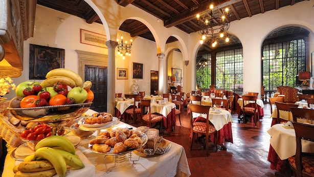 A dining area with tables set for meals, a fruit display, and a chandelier. - Palazzo Monnalisa (Florence)