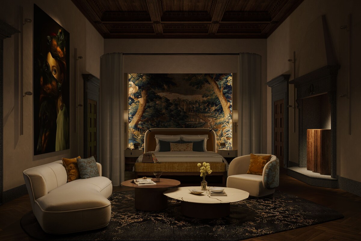 A bedroom with a large bed, two armchairs, a coffee table, and a painting on the wall.