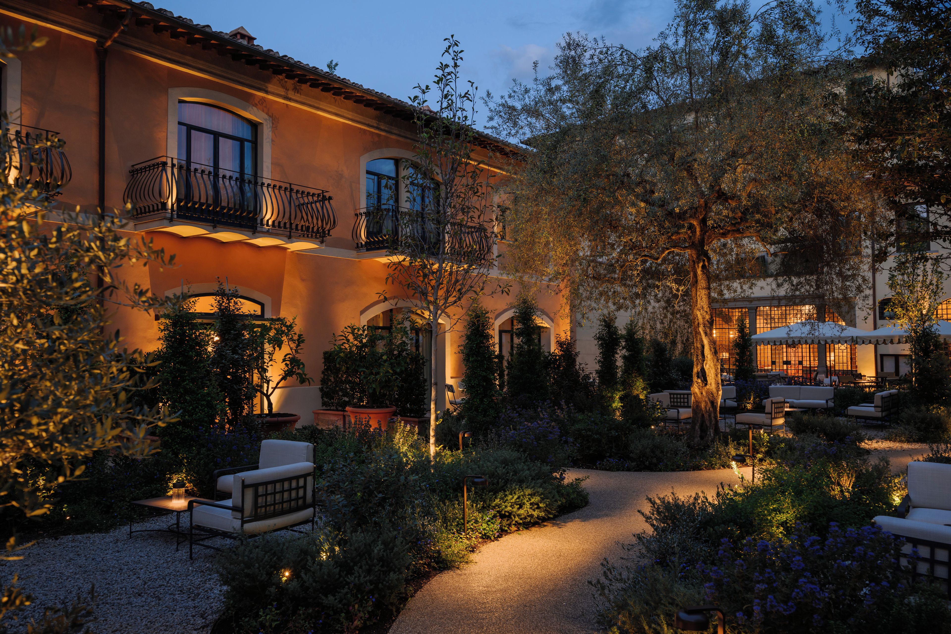 Un patio con mobiliario exterior, un sendero y un edificio con balcones.