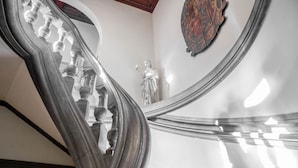 A grand staircase with ornate balustrades and a statue in the background. - Palazzo Monnalisa (Florence)