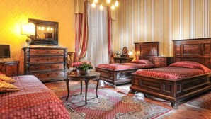 Quarto tradicional com cama de madeira, cômoda, mesa de cabeceira e espelho.