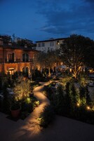 Una vista notturna di un cortile con un vialetto lastricato, circondato da edifici e alberi.