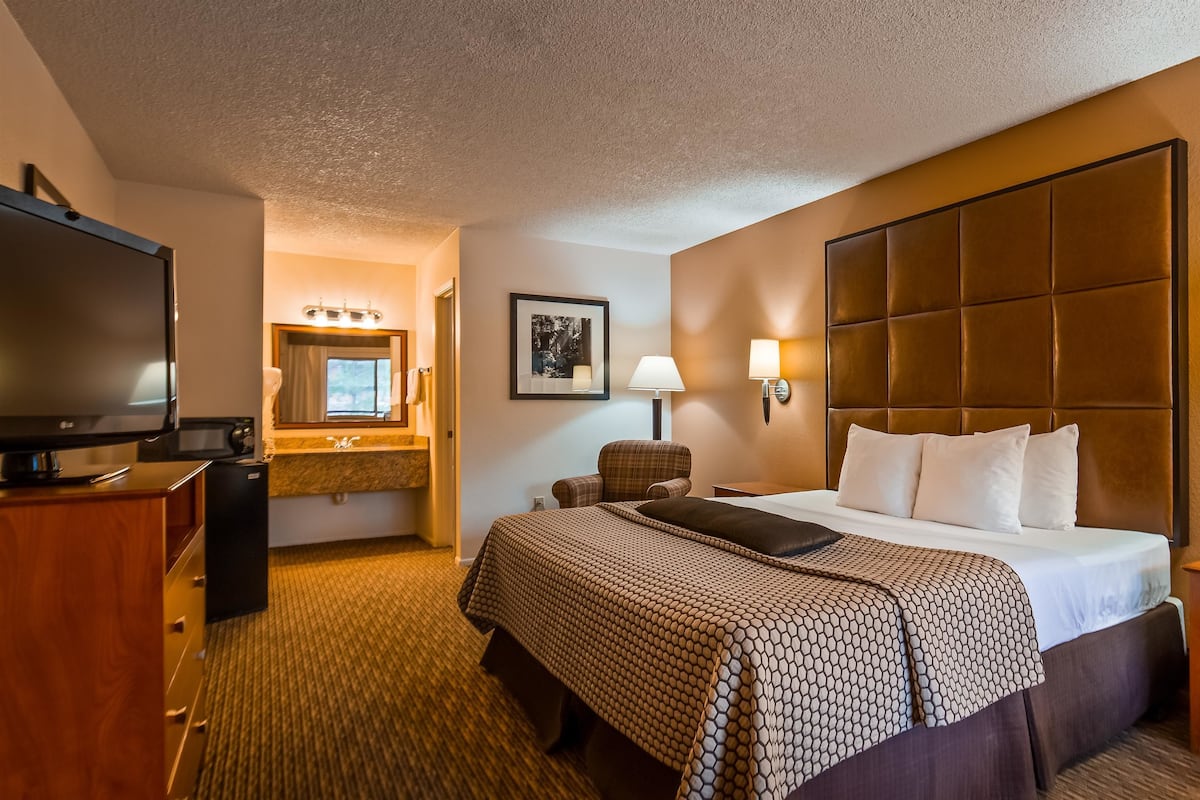 A hotel room with a large bed, a flat-screen TV, a desk, and a chair.