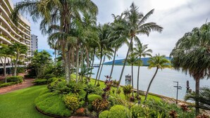 A landscaped garden with palm trees and a view of the water. - Hilton Cairns (Cairns)