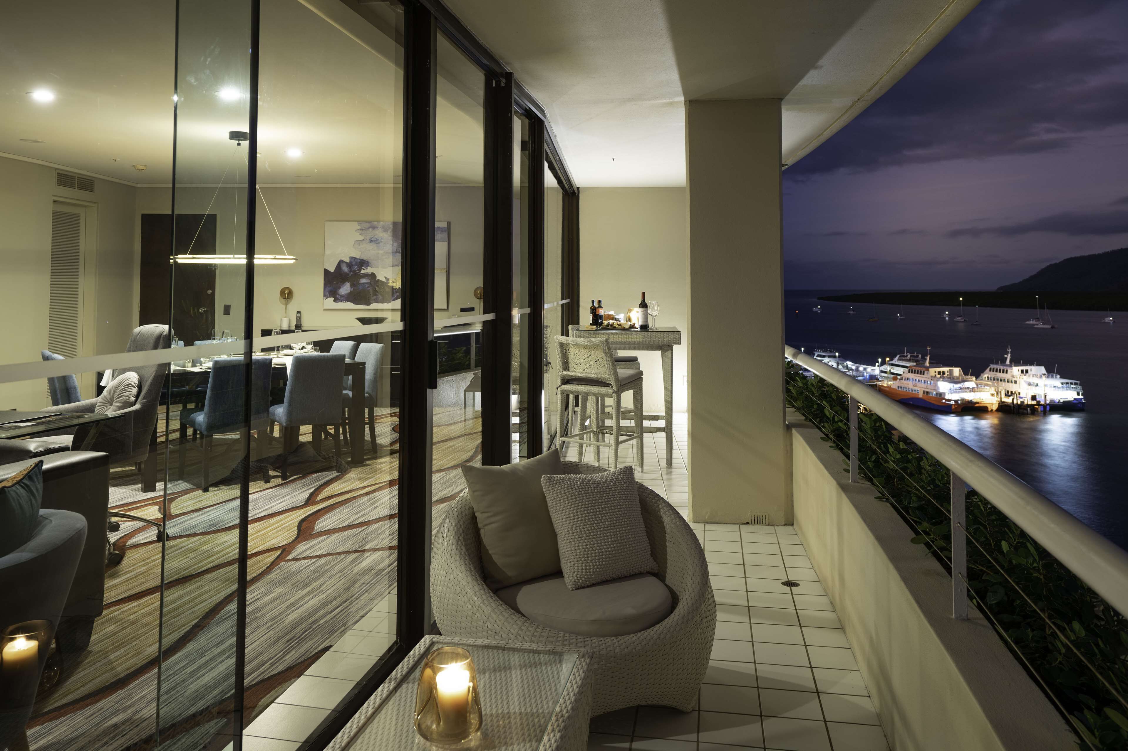 A modern living room with a glass partition, a round seating area, and a dining setup.