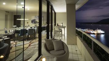 A modern living room with a glass partition, a round seating area, and a dining setup.