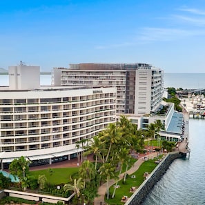 A multi-story hotel with a pool area and a view of the sea. - Hilton Cairns (Cairns)