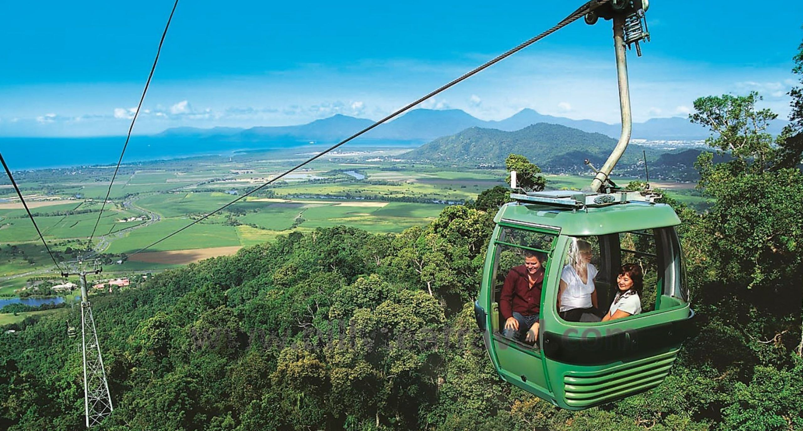 A cable car with passengers, surrounded by lush greenery and a scenic landscape.