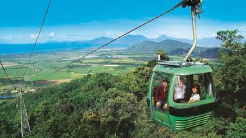 A cable car with passengers, surrounded by lush greenery and a scenic landscape.