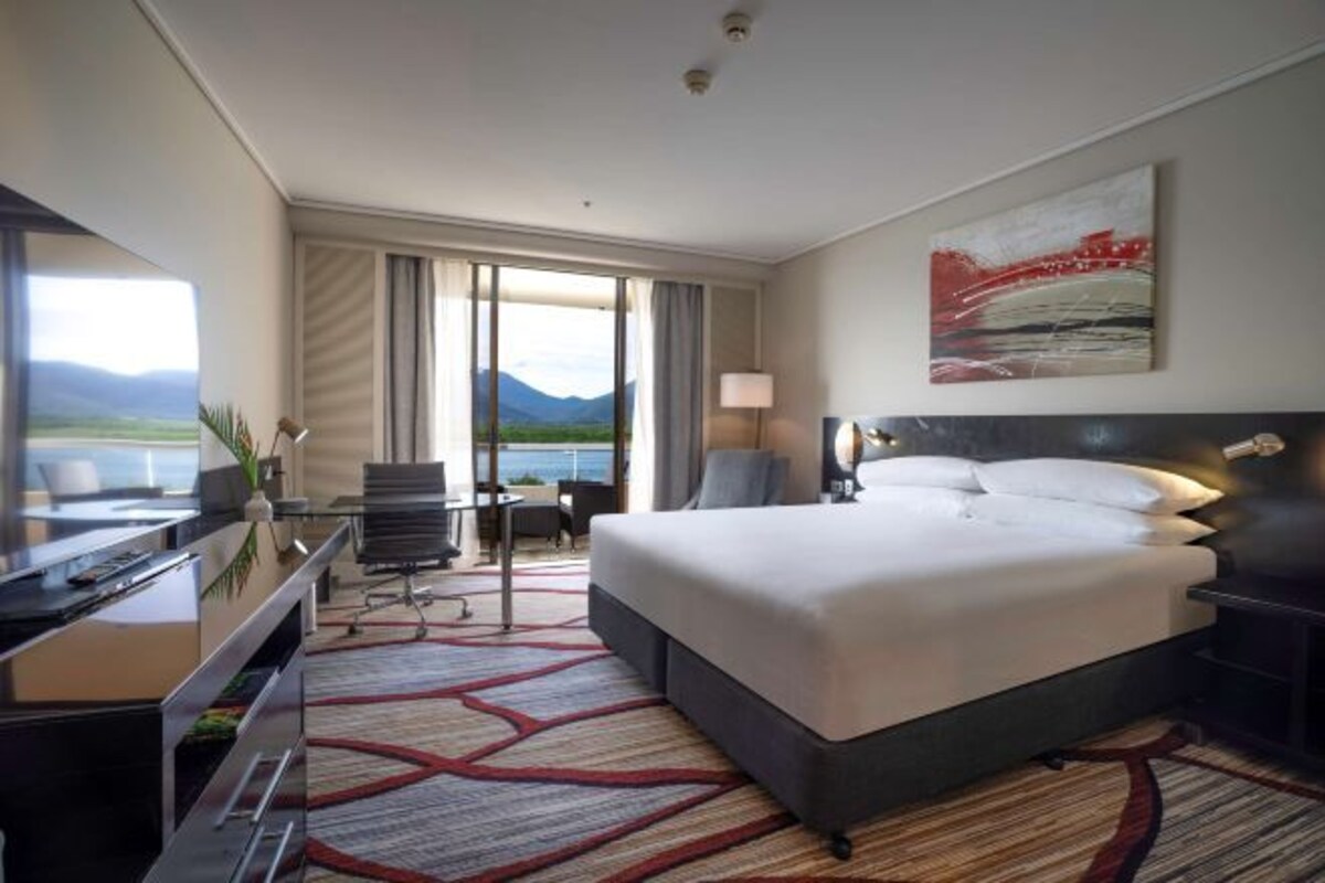 Habitación de hotel con una cama grande, un escritorio con silla, televisión y vistas al exterior.