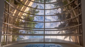 A modern atrium with a curved glass ceiling, allowing natural light to illuminate a patterned floor. - Hilton Cairns (Cairns)