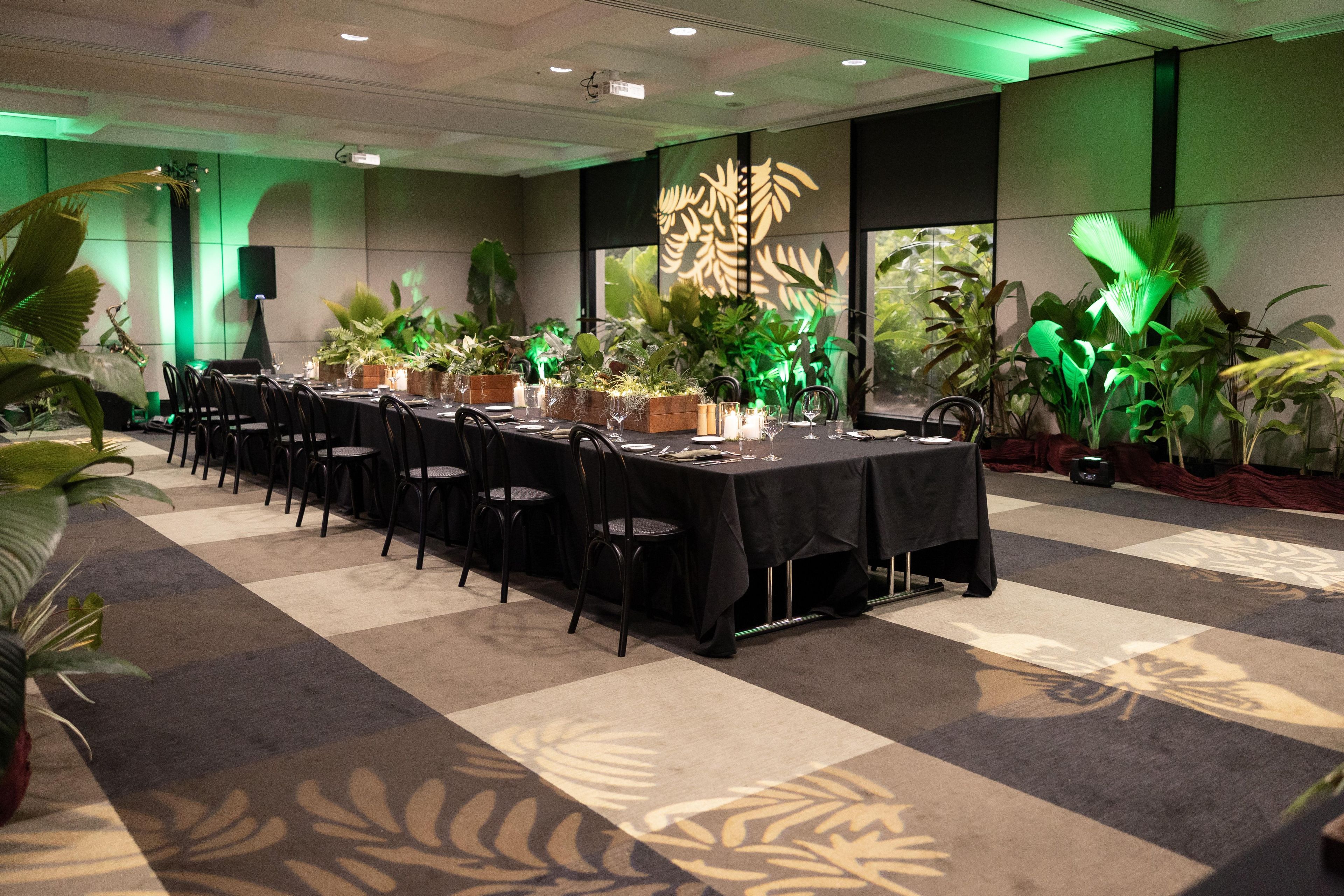 A conference room with a long table, chairs, and potted plants.