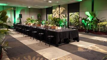 A conference room with a long table, chairs, and potted plants.