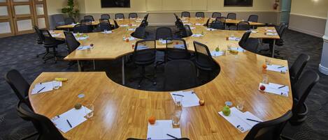 Un salón de conferencias con varias mesas y sillas, equipado con tarjetas de identificación, botellas de agua y documentos.