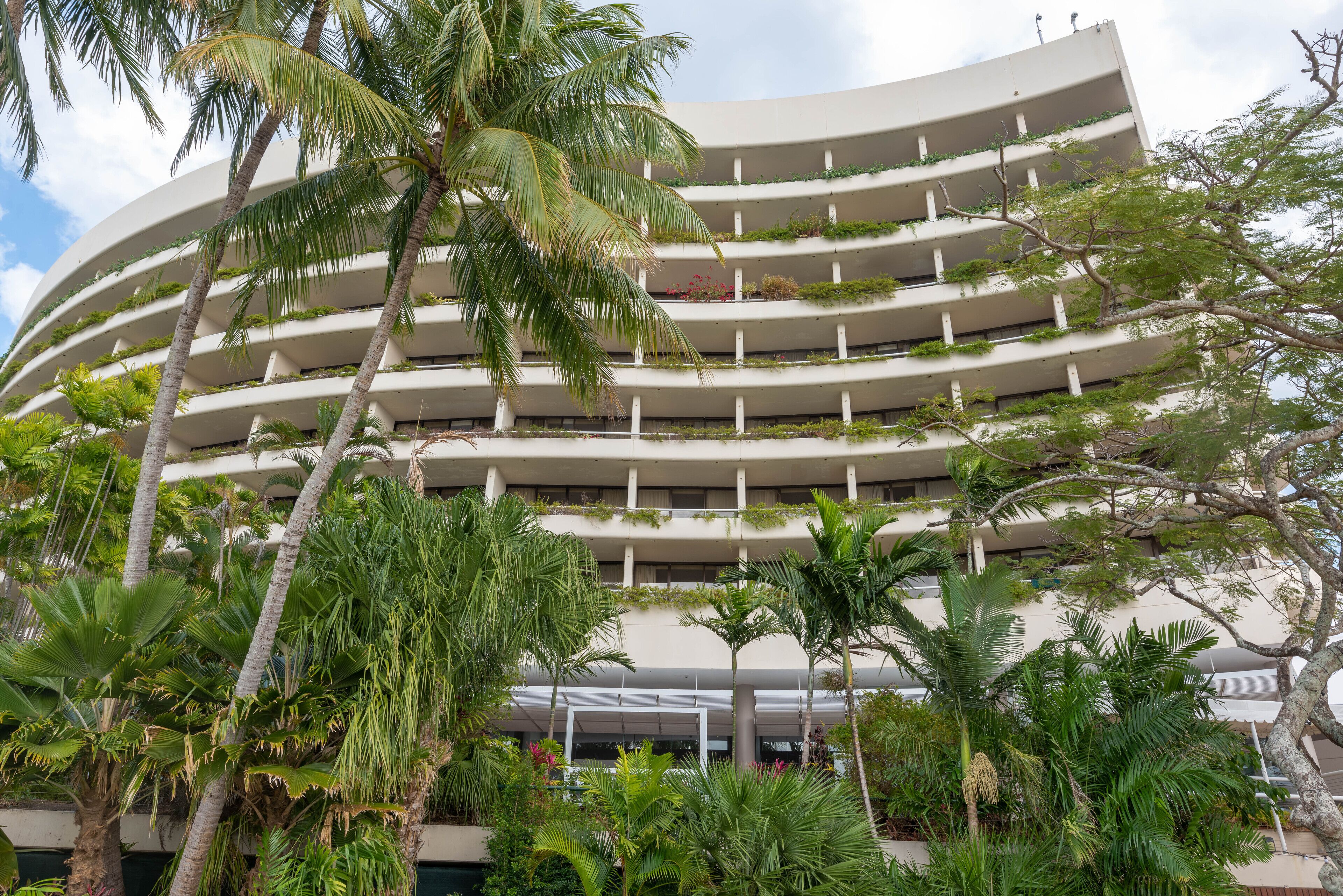 A multi-story hotel with balconies and lush greenery.
