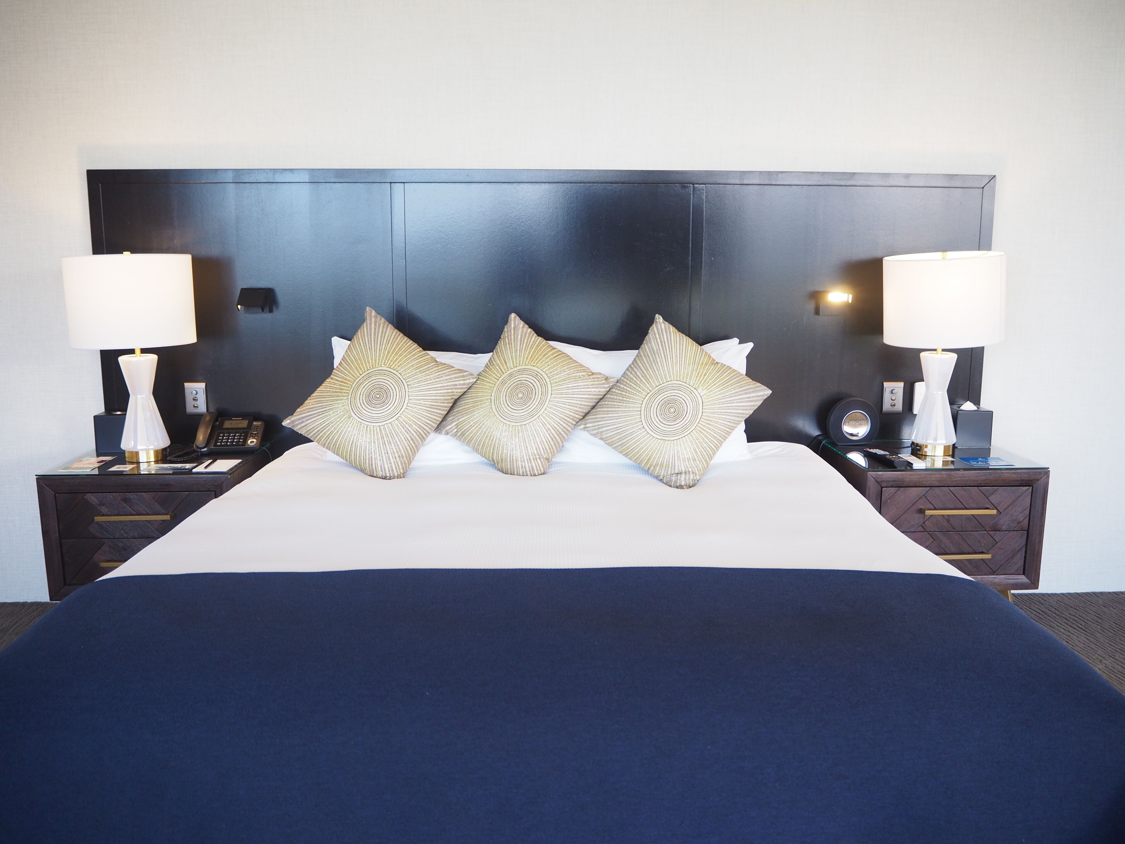 A hotel room with a large bed, two bedside tables, and a headboard.