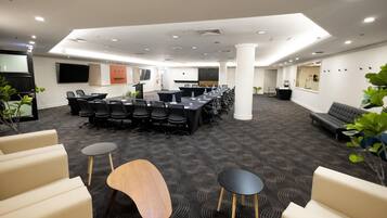 Uma sala de conferências com uma mesa comprida, várias cadeiras e um palco.
