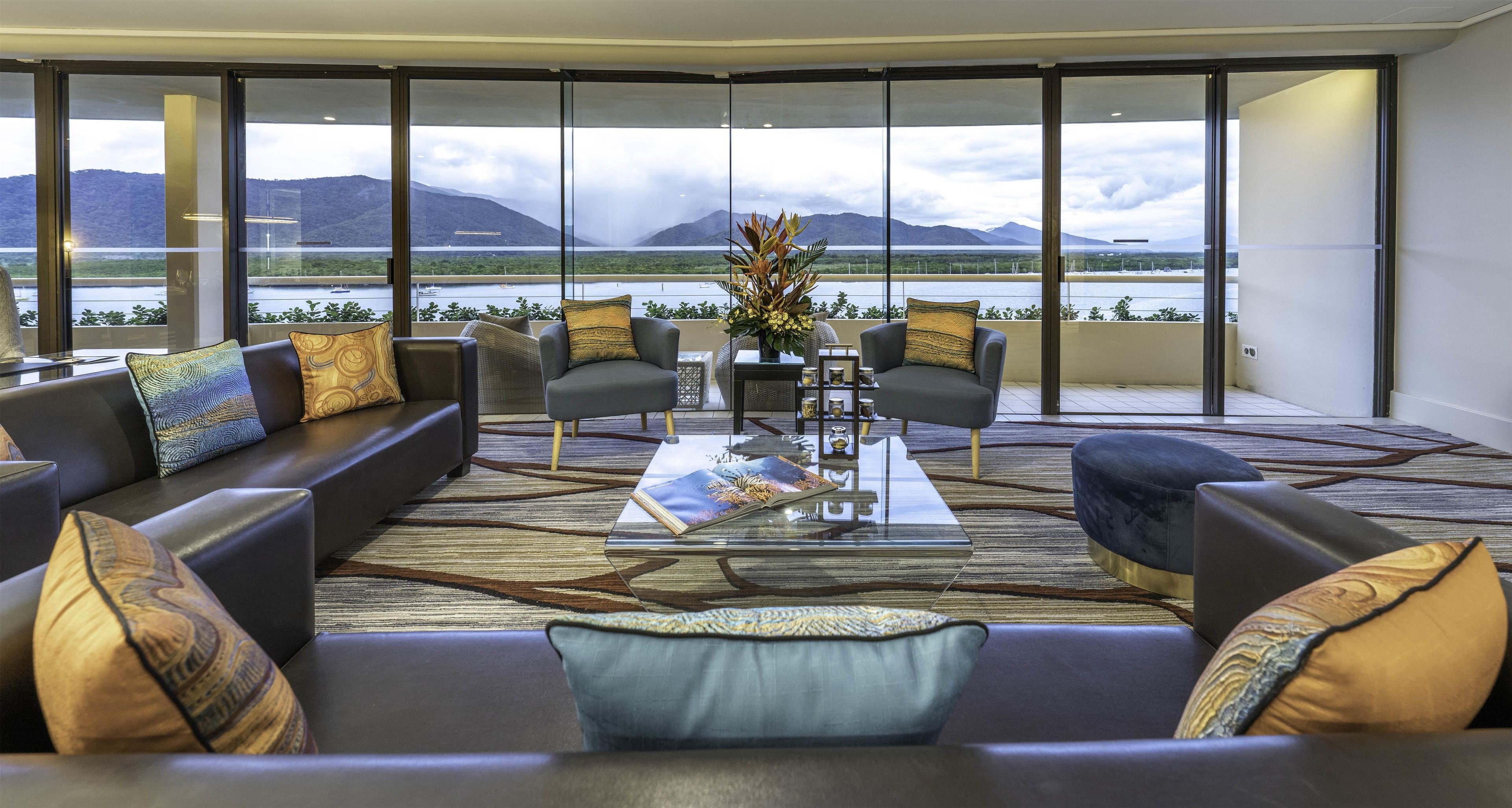 A modern living room with a large view of a lake and mountains.