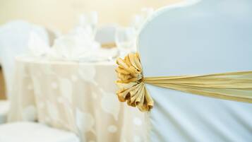 Primer plano de una silla con una cinta dorada atada al respaldo, que sugiere un ambiente para un evento formal.