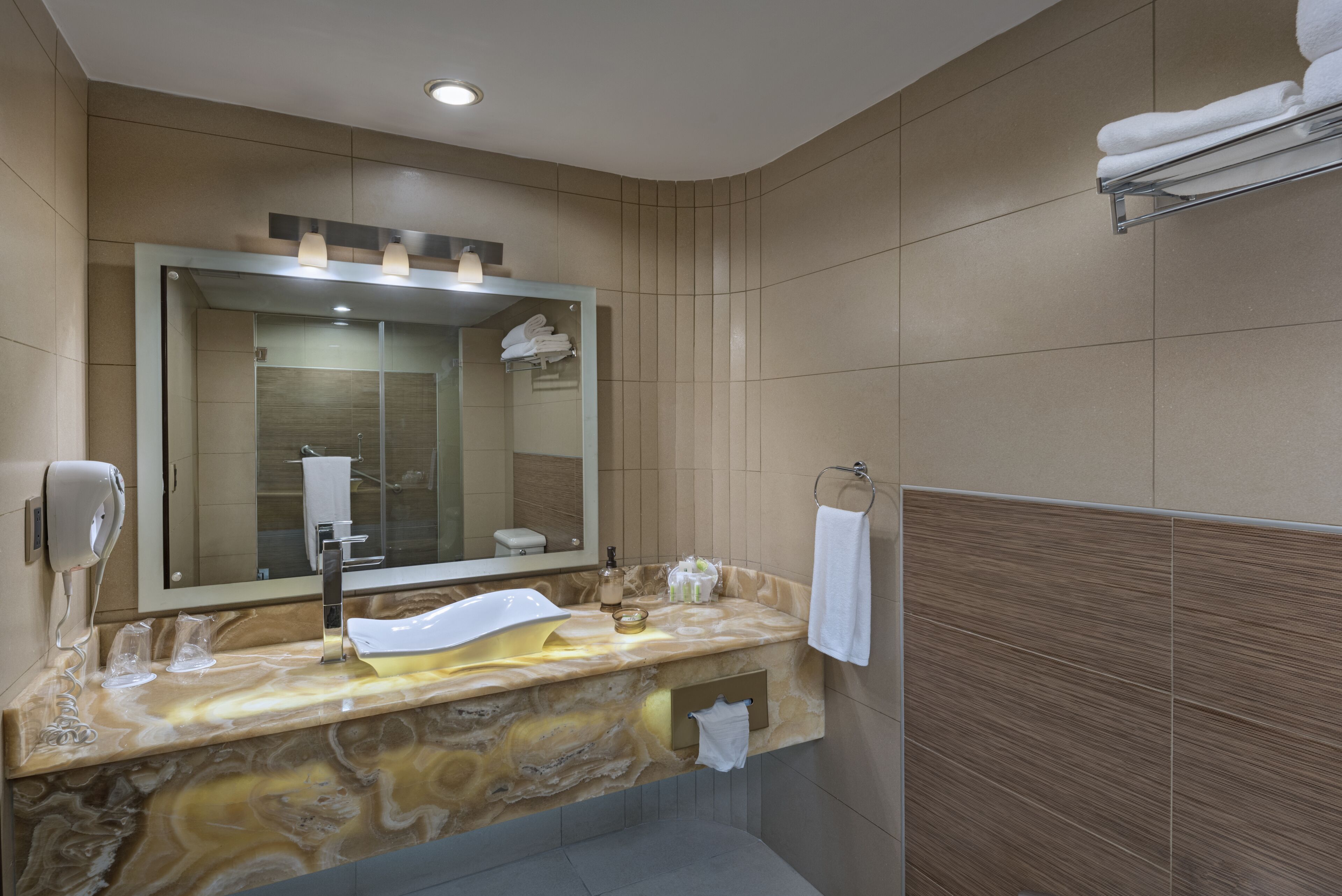 Un baño moderno con encimera de mármol, un espejo grande, un perchero y un lavabo empotrado.