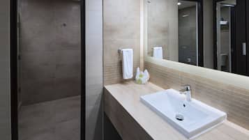 A modern bathroom with a walk-in shower, a large mirror, and a sink with a vanity.
