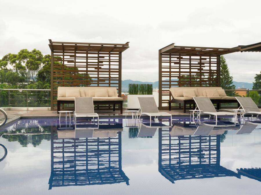 Zona de piscina en la azotea con sillones de descanso y una pérgola de madera.