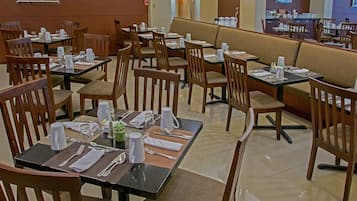 A restaurant with multiple tables and booths, each set with cutlery, plates, and napkins.