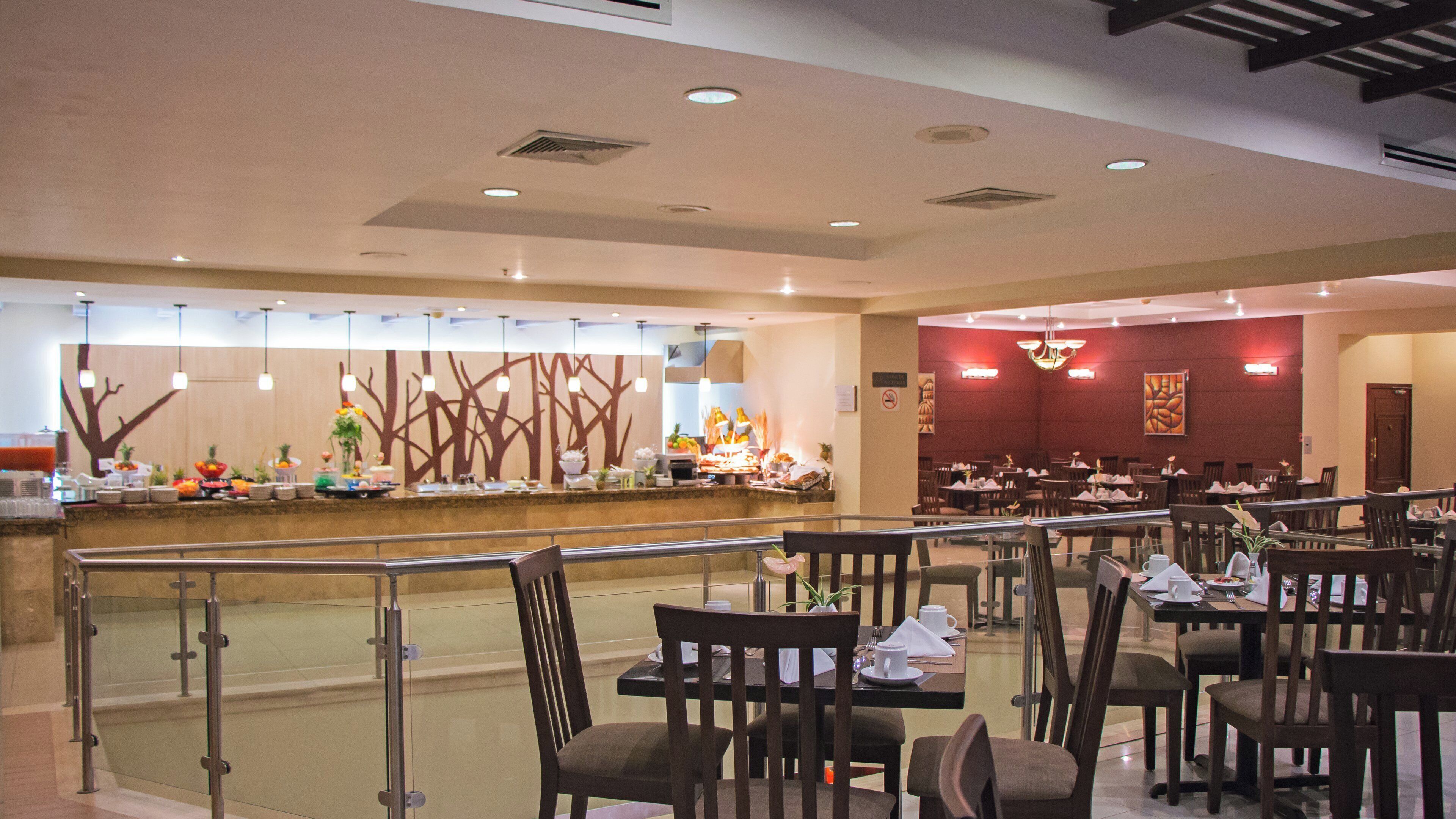 A restaurant with a buffet counter, dining tables, and chairs.