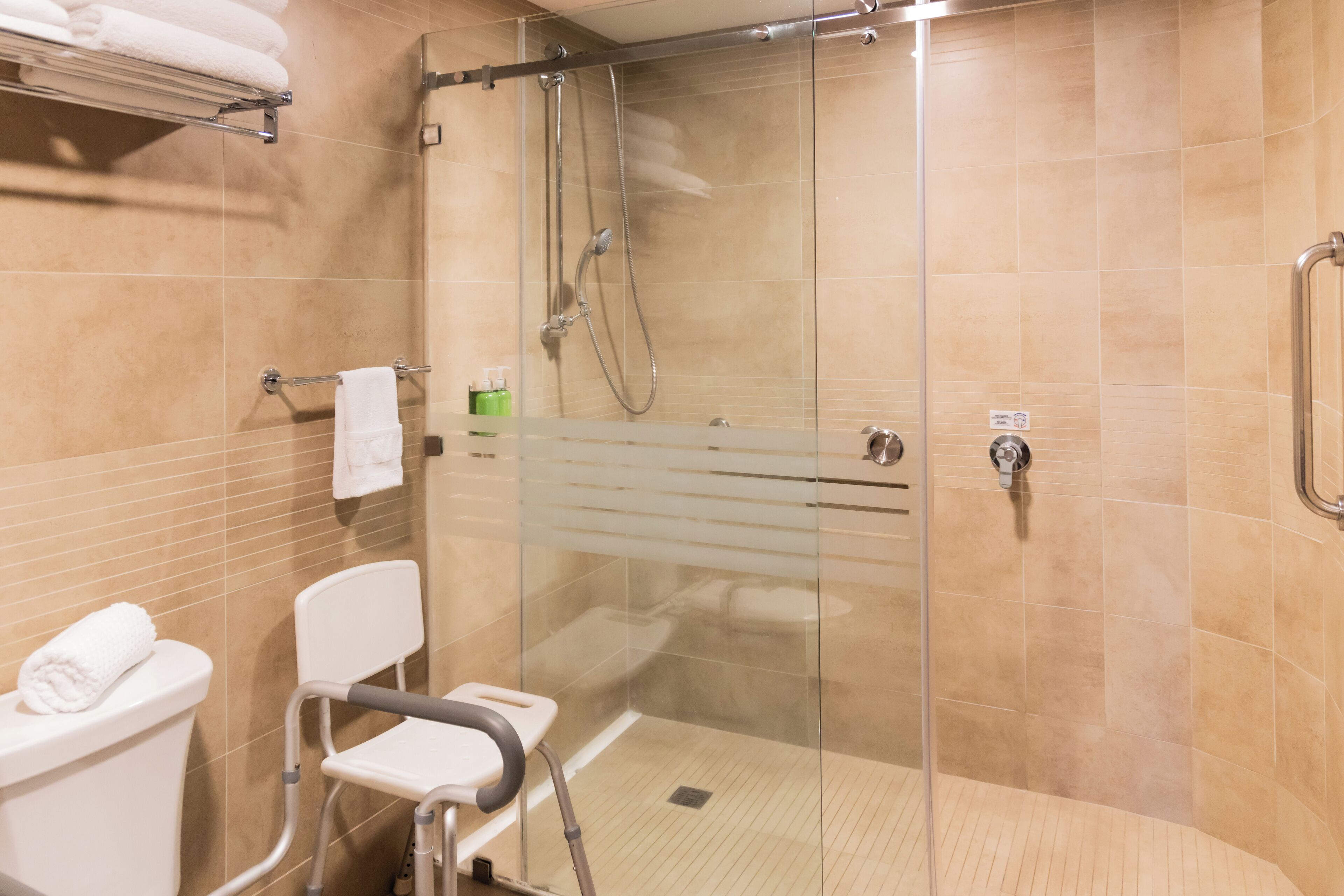A modern bathroom with a glass-enclosed shower, a white toilet, and a white chair.