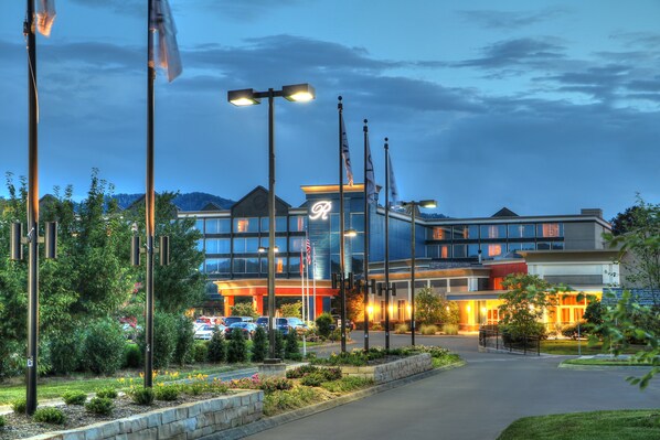 Welcome to a hotel with a symmetrical design, featuring a mix of glass and brick architecture and landscaped gardens.