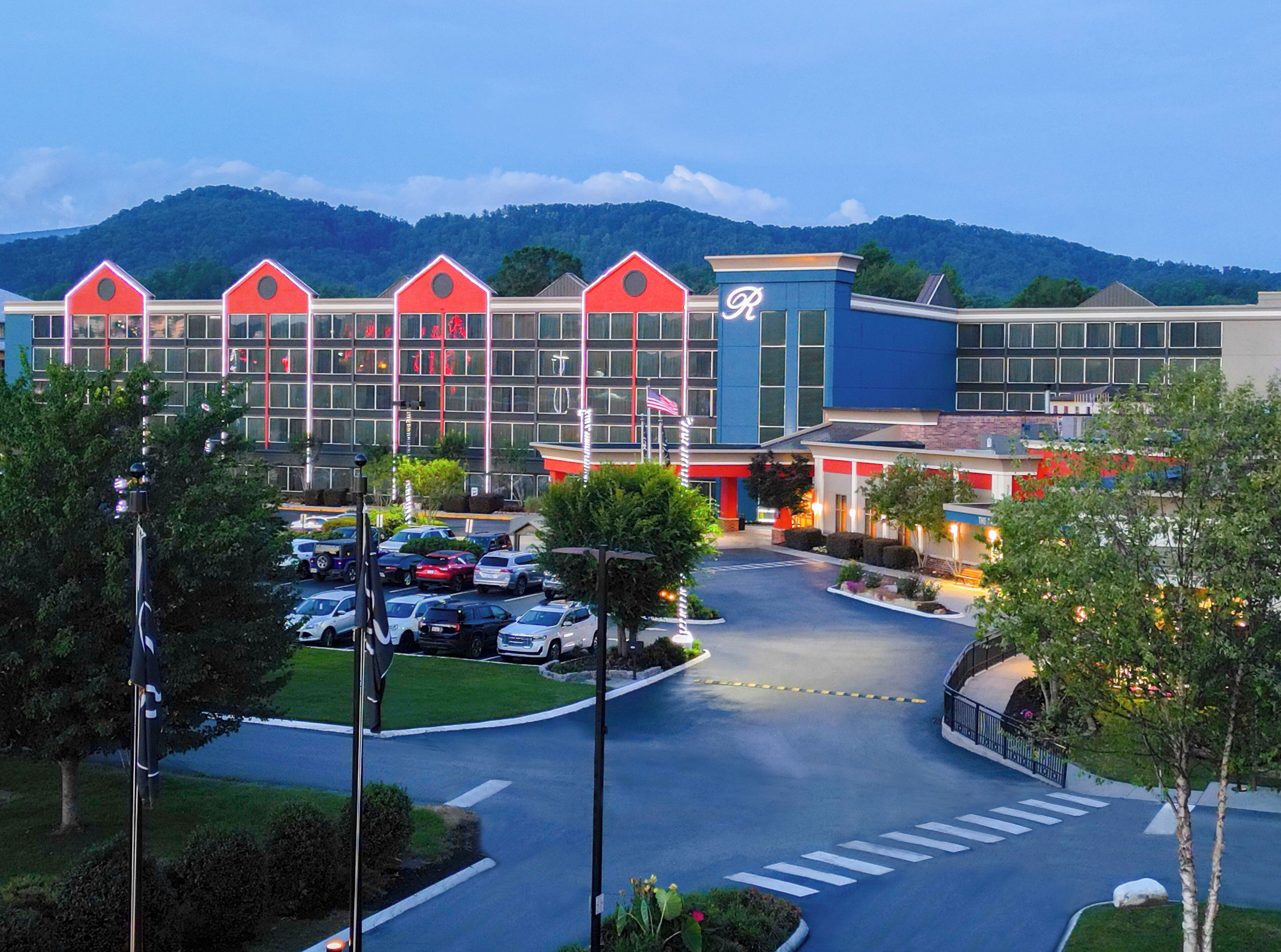 A hotel with a parking lot, multiple buildings, and a mountainous backdrop.
