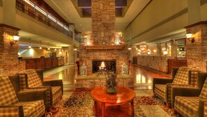A spacious lobby with a stone fireplace, comfortable seating, and a high ceiling with skylights. - The Ramsey Hotel and Convention Center Pigeon Forge (Pigeon Forge)