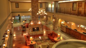 A spacious lobby with a central stone fireplace, multiple seating areas, and a second-floor balcony. - The Ramsey Hotel and Convention Center Pigeon Forge (Pigeon Forge)