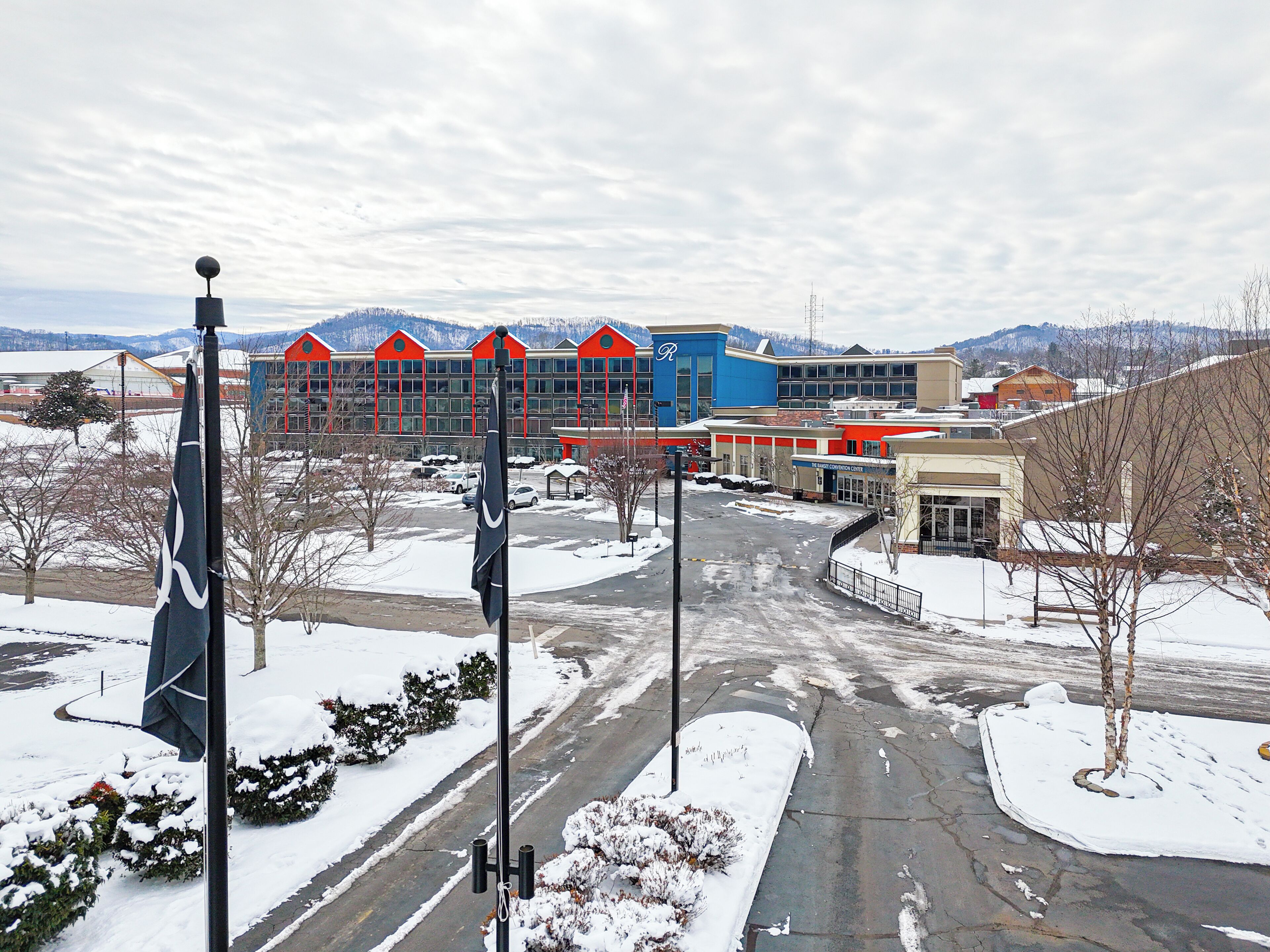 A building with a blue and red facade, a parking lot, and snow-covered ground.
