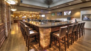 A spacious bar area with a central island, multiple bar stools, and pendant lighting. - The Ramsey Hotel and Convention Center Pigeon Forge (Pigeon Forge)