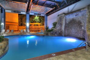 Relax by the serene pool surrounded by a seating area and shaded pergola.