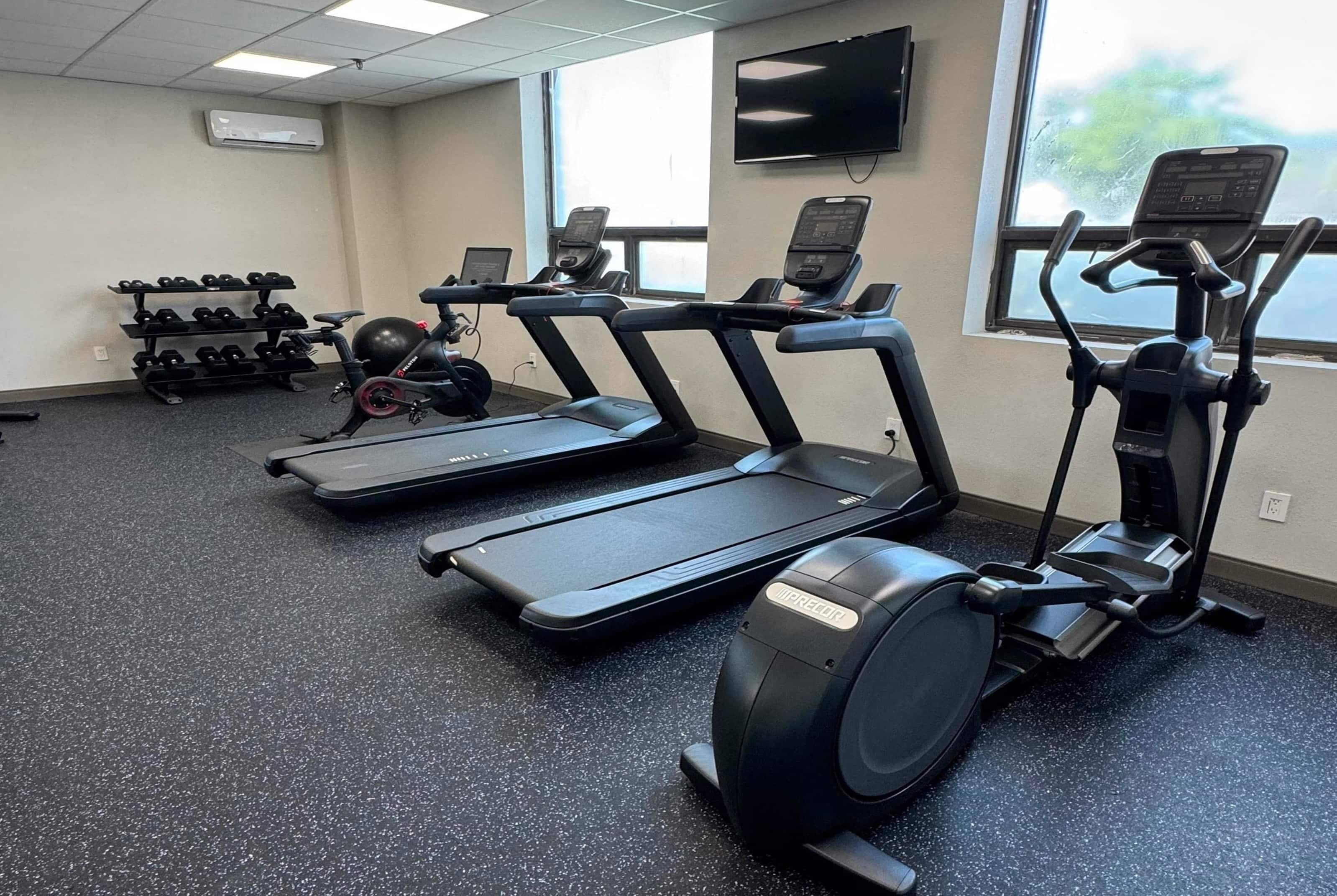 A gym with treadmills, an elliptical, and a weight rack.