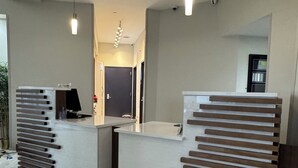 Een receptie met twee balies, een flatscreen televisie en een moderne lamp.