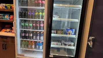 Two beverage dispensers, one with a freezer and one without, stocked with various drinks and snacks.