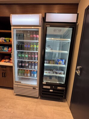 Two beverage dispensers, one with a freezer and one without, stocked with various drinks and snacks. - La Quinta Inn & Suites by Wyndham New Haven (New Haven)