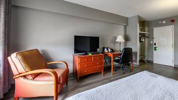 Habitación de hotel con cama, escritorio con televisor, silla y cómoda.