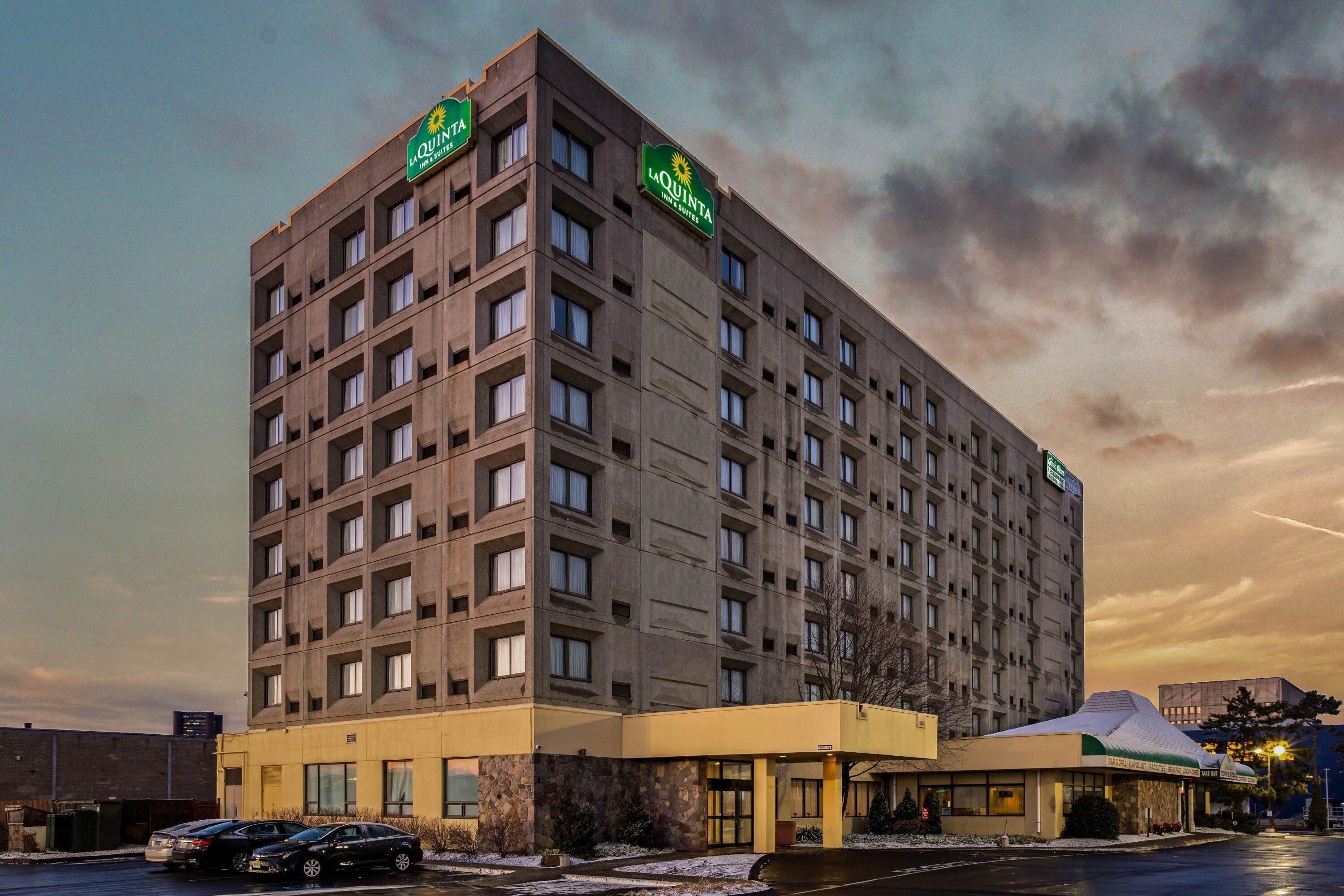 Ett hotell med flera våningar, en slät fasad, många fönster och en grön skylt som visar att det är ett La Quinta Inn & Suites.
